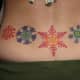 Colorful lower back snowflake tattoos.