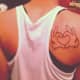Shoulder tattoo with hands in shape of love heart.