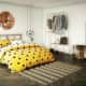 A bold comforter in yellow with black dots plays to the Hufflepuff colors. The room also has a certain simplicity to it that's charming, clothes hang openly and there is a vase of flowers.