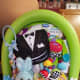 Baby Easter basket. Dollar Tree clothes basket and pool noodle, hot glue and decorations. Place a wrapped piece of cardboard in the middle of basket to hot glue items up the cardboard, for a more professional look.