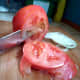 Utility knife slicing a tomato