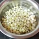 Add 1/2 cup of sweet corn kernels to a pot. Add 1/2 cup of water and cook.