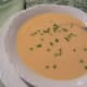 A serving of carrot vichyssoise in a bowl topped with snipped chives