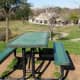 One of two picnic tables on top of a hill in the park overlooking the pavilion, sports field, and parking lot