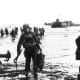 Carrying their equipment, US assault troops move onto Utah Beach. Landing craft can be seen in the background. Among them would be J.D. Salinger the author of &quot;The Cather in the Rye.&quot;