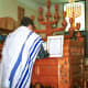A man wearing a tallit, a traditional Jewish prayer shawl while worship.