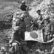 U.S. Marines (Left to Right), PFC. J. L. Hudson Jr. Pvt. K.L. Lofter, PFC. Paul V.Parces, (top of blockhouse), Pvt. Fred Sizemore, PFC. Henrey Noviech and Pvt. Richard N. Pearson pose with a captured Japanese flag on top of enemy pillbox.