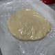 Gently, flatten the dough before covering it loosely with cling wrap. 