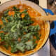 The bright green kale leaves contrast with the orangeness of the stew.