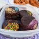 The container is holding moon pies. A moon pie is a cookie sandwich coated in chocolate. The centers have marshmallow filling and jam.