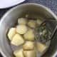 Drained potato pieces are hand mashed
