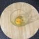 Egg is broken in to a small glass and seasoned
