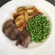Goose breast slices are plated with wedges and peas