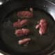 Goose strips are added to searingly hot frying pan
