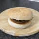 Seeded bun top is laid on goose, potato and onion