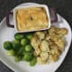 Pigeon and mushroom pie is plated with sprouts and cheese and onion roasties