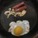 Duck egg is poured in to frying pan with sausages and onion