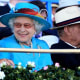 The Queen smiles during a day at the races while the Duke of Edinburgh uses binoculars to watch the field of horses