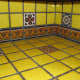 Yellow talavera tile kitchen countertop with border and single pattern tiles.