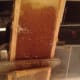 Cutting wax off a bee frame with a hot knife.