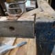 Widening the gap at the top of the chair with a wooden mallet, where any of the joints are loose, in preparation for gluing.