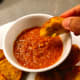 Dipping the cucur udang into the sauce.