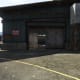 Take cover by this doorway at the left end of the building.