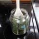 Using a wood spoon to push the leaves into the jar and slightly bruise them to aid infusion of the oils.