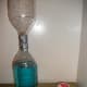 The materials for a tornado experiment: 2 bottles, tape, glitter, and food coloring.