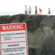 This family of five daredevils crossed a fence and ignored a large warning sign to stand on that cliff. Who's leading here?