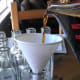 Pouring the finished liqueur into decorative bottles.