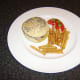 Pork leg steak on a bun with cheese, garlic mushrooms and fries is ready to serve