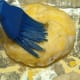 Place boiled bagels on a baking sheet lightly sprinkled with cornmeal, and then brush the top of each bagel with the egg yolk mix.