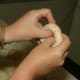 Holding the dough ball with both hands, place your thumbs in the center of the roughest side of the ball...