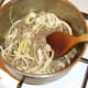 Sliced onion is stirred in to browned beef.