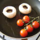 The tomatoes and mushrooms are added to a separate pan.