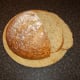 Slicing wheat, spelt and rye bread for serving with beef and chestnut soup