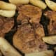 Pork chops are hot, tender and ready to serve with potatoes sprinkled with rosemary leaves.