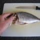 A deep cut is made around the head of the sea bream