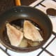 Sea bream fillets are added to frying pan skin sides down