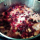 The arrowroot mixture is added. It will be stirred into the cranberry-apple mixture. The white color will disappear.