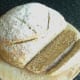 Slice of wheat, spelt and rye bread is cut to serve with kangaroo and vegetables