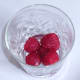 Frozen raspberries added to cocktail glass