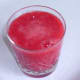 Strained raspberry cocktail mix poured over frozen raspberries