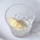 Wedge of frozen lemon is added to a glass for cocktail