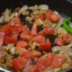 Step four: Throw in chopped tomatoes, pepper corns, a piece of nutmeg, and a cinnamon stick. Stir-fry till tomato becomes soft.