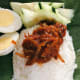 Assemble the sambal ikan bilis on top of the rice, hard-boiled eggs, and fresh sliced cucumbers. Serve in on top of banana leaf for the best and most authentic nasi lemak.