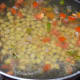 Step five: Add cooked hyacinth beans or green peas. Add 6 cups of water. Bring the mix to a boil. Add salt and sugar. Lower the heat.