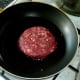 Burger is added to frying pan