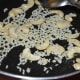 Step one: Heat ghee in a pan. Add cashew nuts. Saute for a few seconds. Add raw rice. Continue sauteing till the rice puffs up a little.